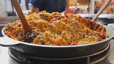 在大锅里煮皮拉夫。 大锅里有肉和蔬菜的米饭。 亚洲传统菜肴-皮拉夫。 全国美味